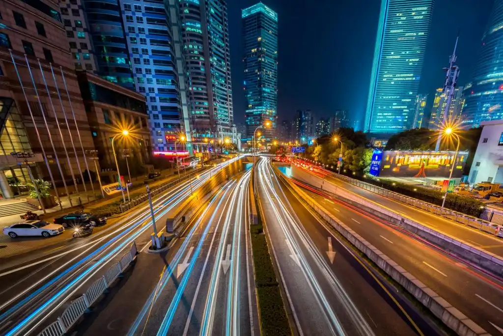 Timelapse photography of vehicle on concrete road near in high rise building during nighttime