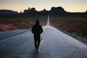 A person walking into the sunset.